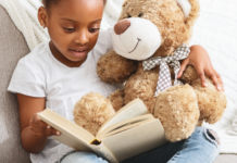 A girl reading a book series to her Teddy bear.