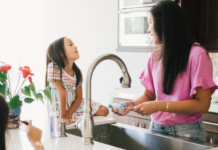 A woman doing the dishes talking to her daughter.