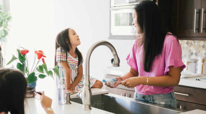 A woman doing the dishes talking to her daughter.