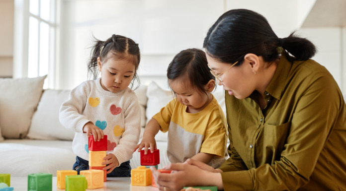 A mom building blocks with her two young daughters.