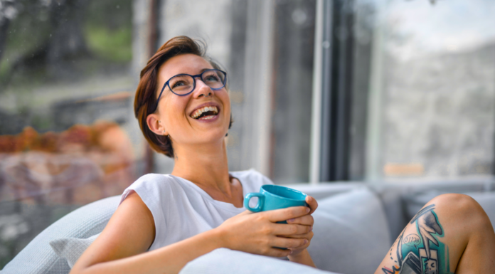 A woman smiling drinking coffee.