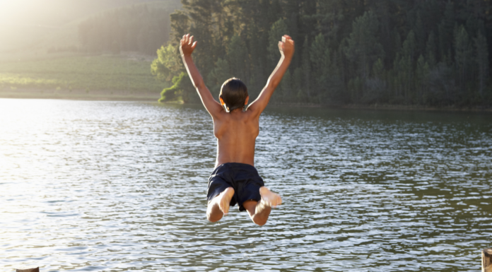 A boy jumping into a lake.