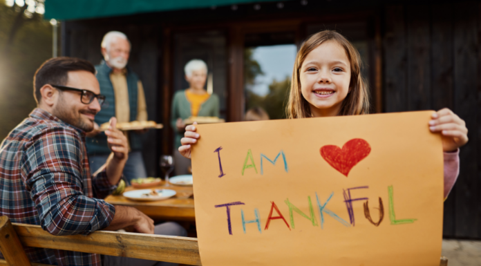 A girl holding a sign that says, "I am thankful."