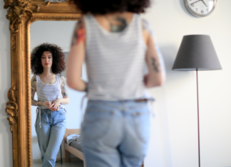 A woman looking at a herself in a full length mirror.