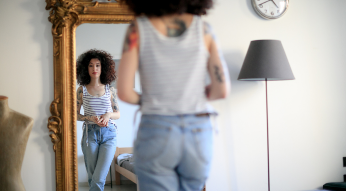 A woman looking at a herself in a full length mirror.