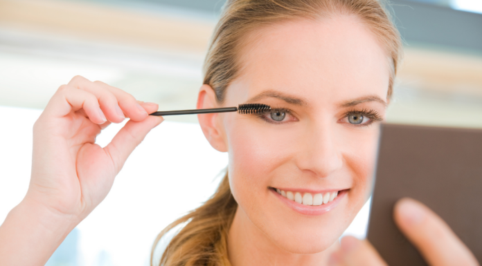 A woman applying mascara.