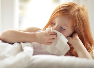 A girl blowing her nose into a tissue.