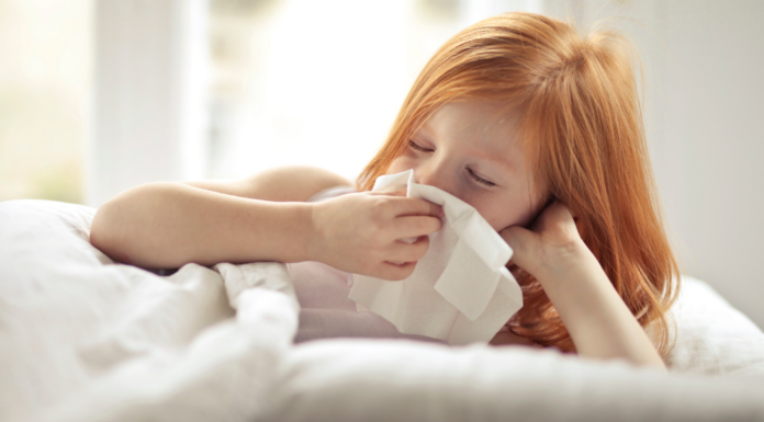 A girl blowing her nose into a tissue.