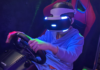 A boy holding a steering wheel while playing a VR car simulation game.