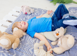 A boy laying on a blanket with stuffed animals.