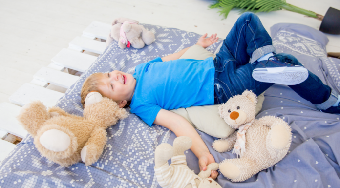A boy laying on a blanket with stuffed animals.