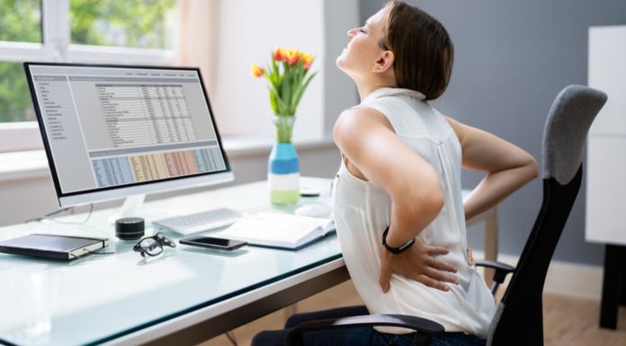 Mom’s Pain Points A woman experiencing back pain while sitting in front of her computer.