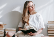 A mom reading next to stacks of books.