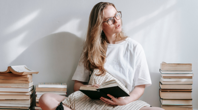 A mom reading next to stacks of books.