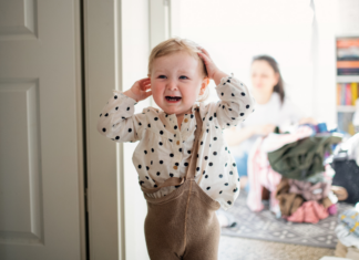A toddler with their clothes on crooked.