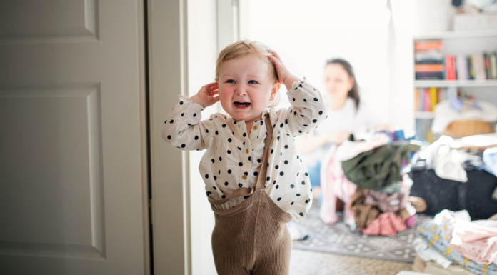 A toddler with their clothes on crooked.