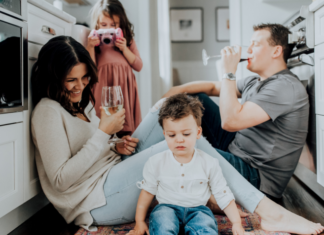 A couple drinking wine while their kids play.