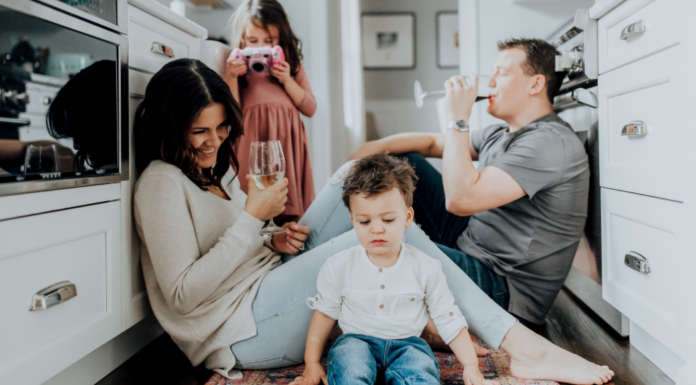 A couple drinking wine while their kids play.