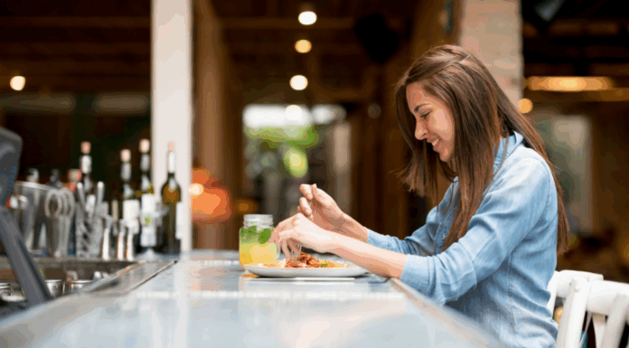 A woman eating at a bar alone.