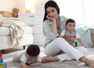 A mom sitting on the floor with two babies.