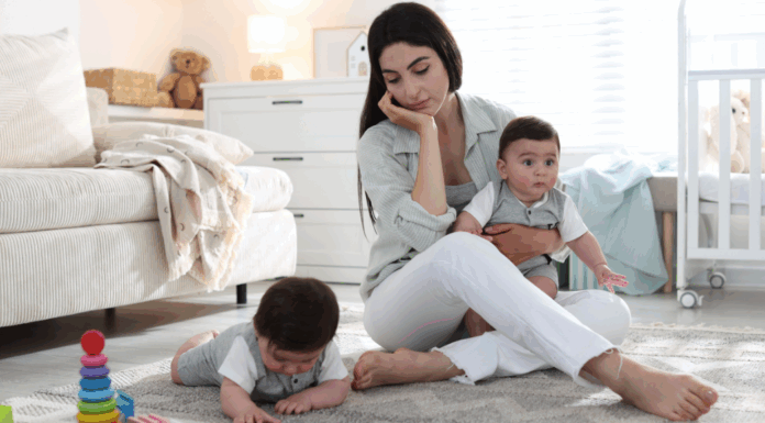 A mom sitting on the floor with two babies.