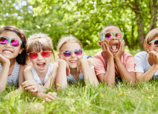 A group of friends wearing sunglasses laying on the grass.