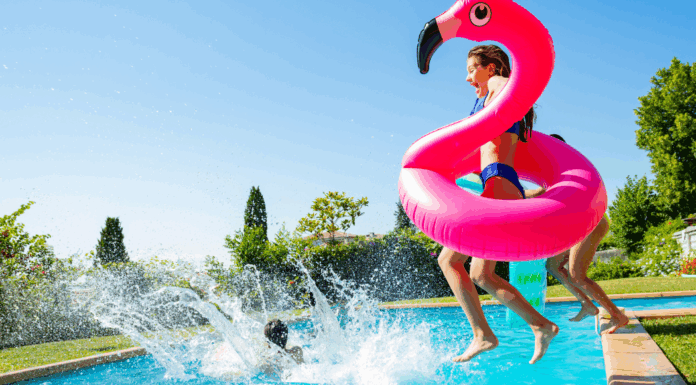 A mom jumping in a pool with her kids.