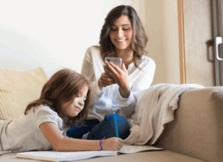 A mother on a phone while her kid does school work.