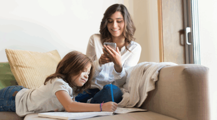 A mother on a phone while her kid does school work.
