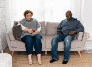 A couple on the couch looking at their phones.