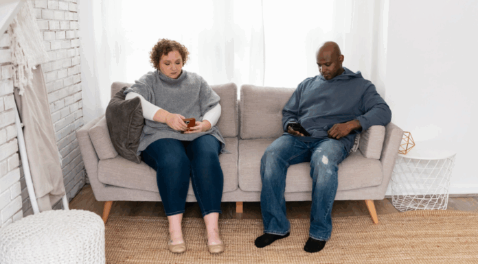 A couple on the couch looking at their phones.