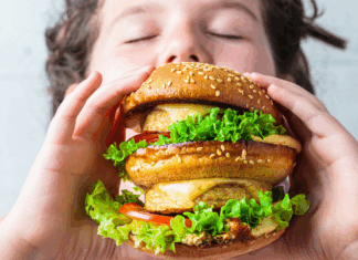 A kid eating a massive burger.