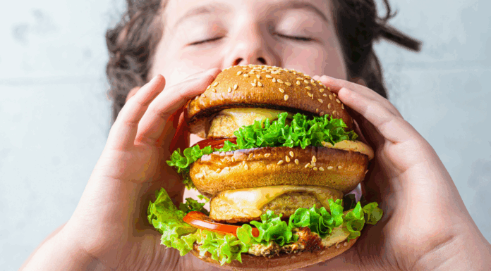 A kid eating a massive burger.