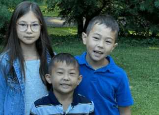 A first day of school photo of three siblings.