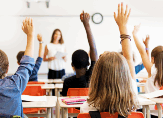 Kids raising their hands in a classroom.