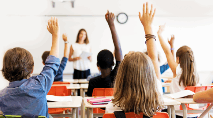 Kids raising their hands in a classroom.