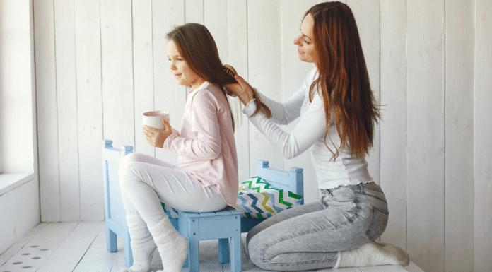 A mom doing her daughter's hair.
