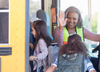 A school bus driver high-fiving a child getting on the bus.