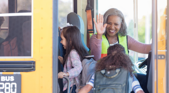 A school bus driver high-fiving a child getting on the bus.