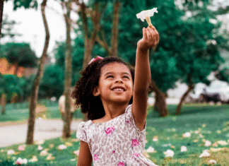 A girl holding up a flower.