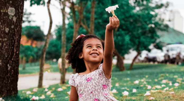 A girl holding up a flower.