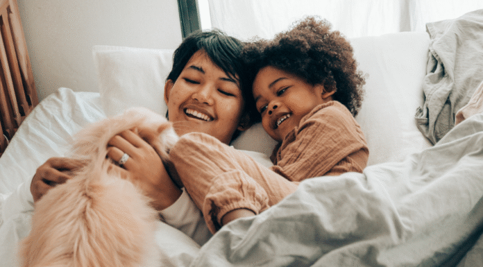 A mom laying in bed with her child and cat.