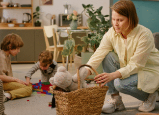 A woman picking up toys while her kids are playing.