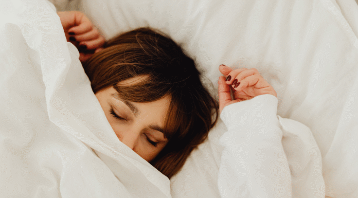 A woman sleeping under covers.