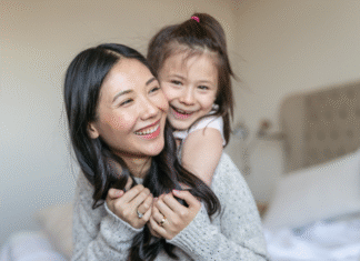 A daughter hugging her mom from behind.