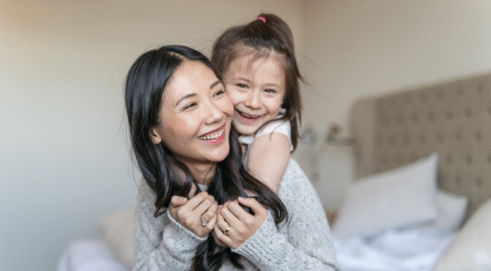 A daughter hugging her mom from behind.