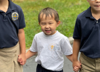 A boy holding hands with his siblings.