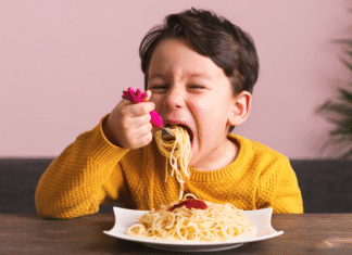 A boy eating a plate of spaghetti.