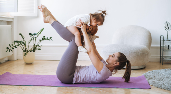 A woman doing yoga while holding her toddler.