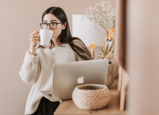 A woman drinking coffee and looking at the computer.